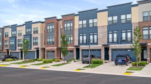 Exterior view of townhomes left center with cars and drives